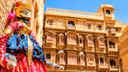 Traditional Rajasthani puppet in colorful attire with historic sandstone haveli architecture